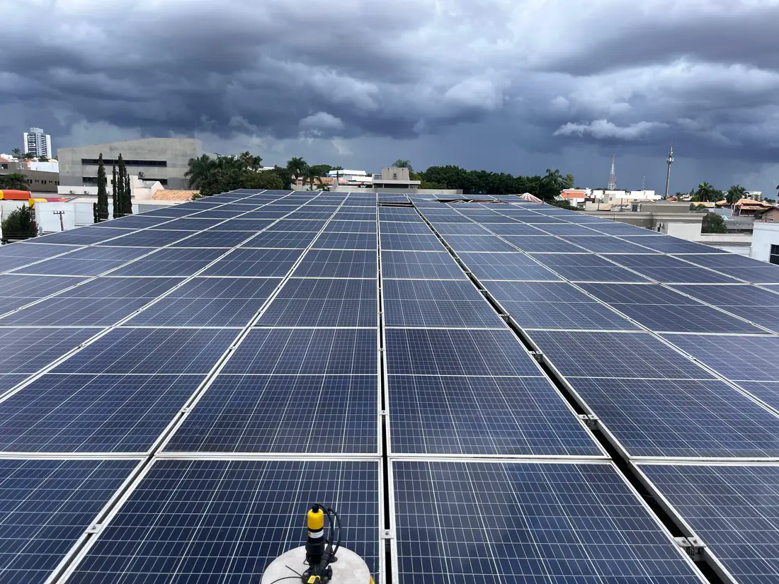 Cobertura comercial totalmente ocupada por módulos fotovoltaicos, com a cidade ao fundo