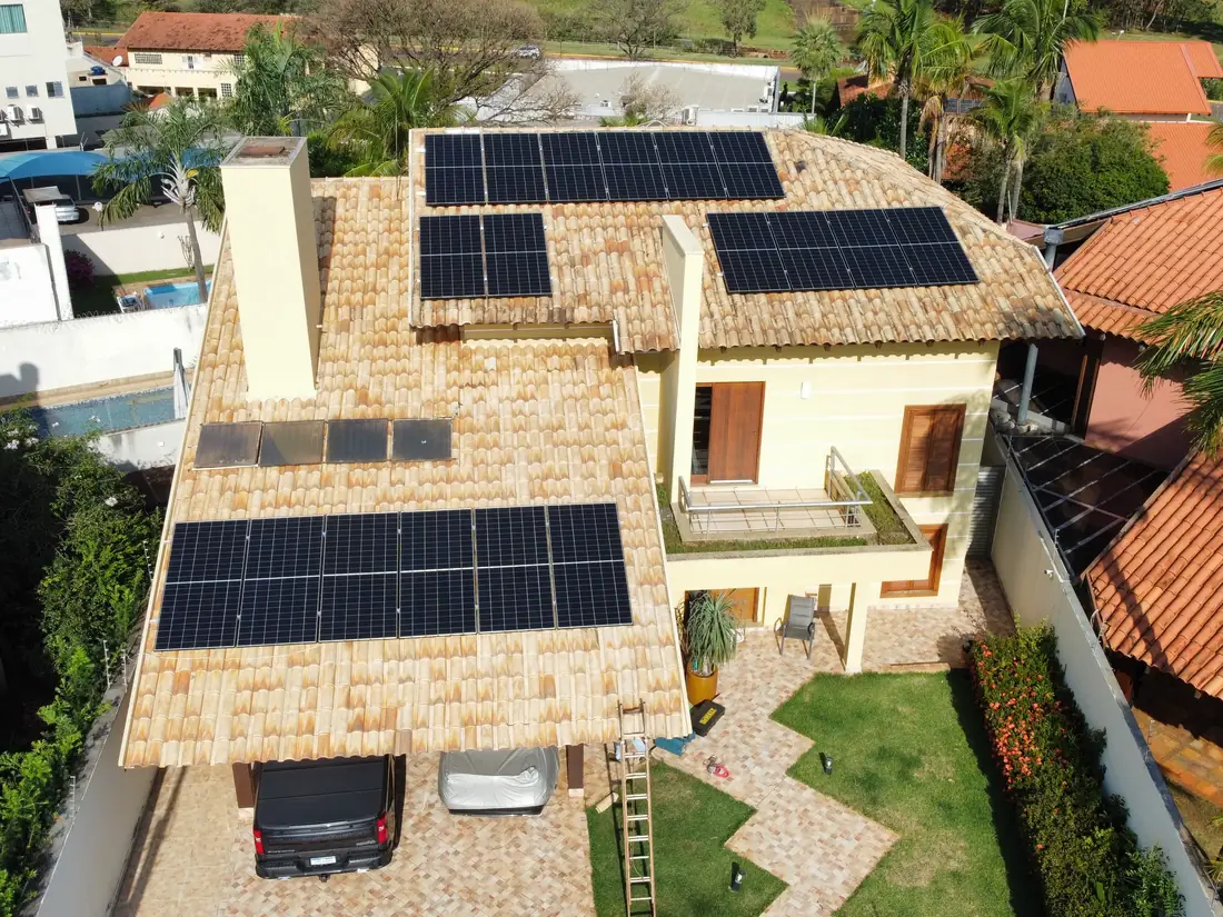 Vista aérea de residência em telha cerâmica com três conjuntos de módulos fotovoltaicos instalados no telhado
